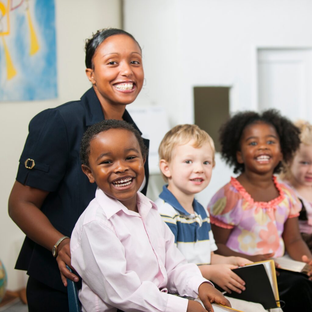 Primary school teacher leading a reading session with young pupils in a bright classroom.