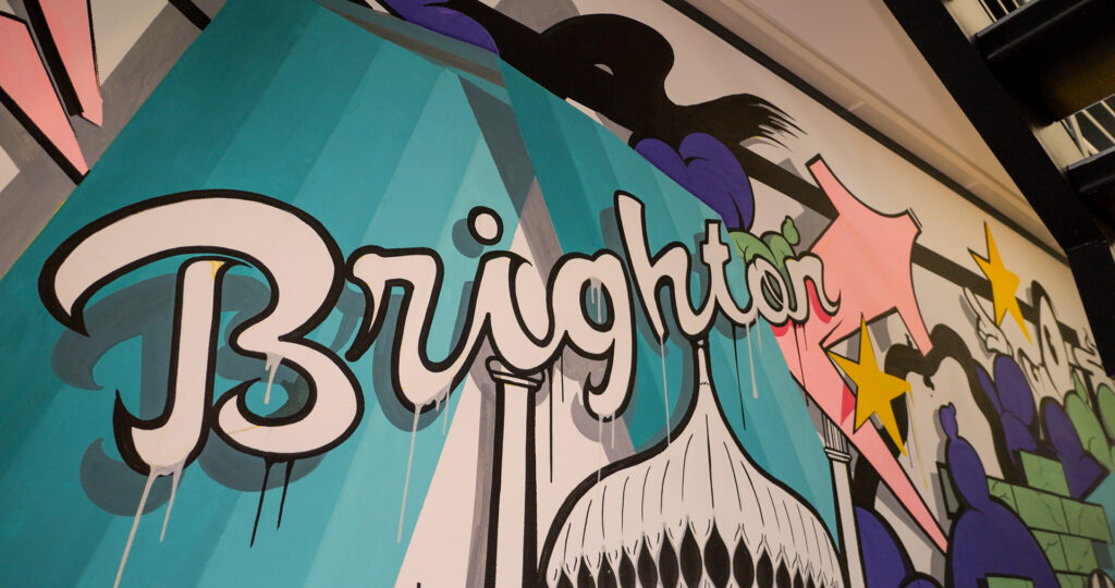 Colourful Brighton street art mural featuring the word "Brighton" in bold graffiti lettering.